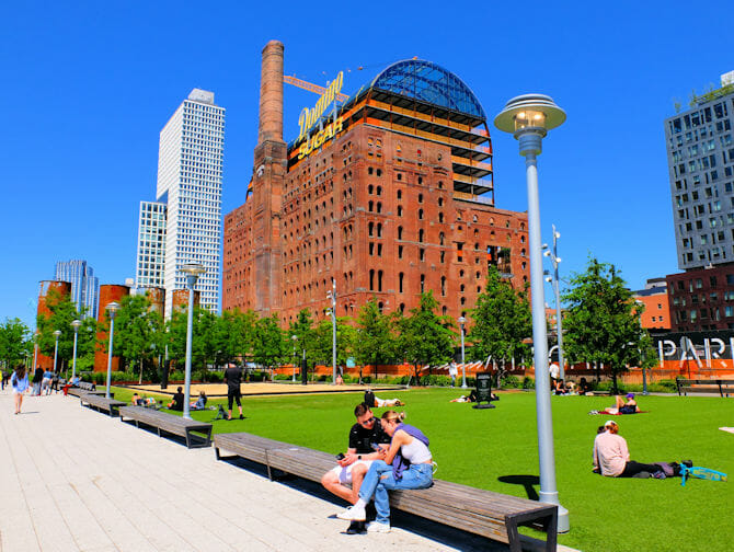 Dia ensolarado em um parque de Williamsburg, no Brooklyn, com pessoas sentadas curtindo o dia.